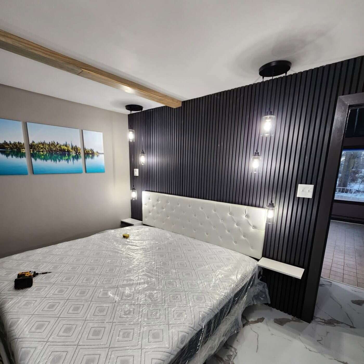 Guest bedroom with black slat accent wall and pendant lighting