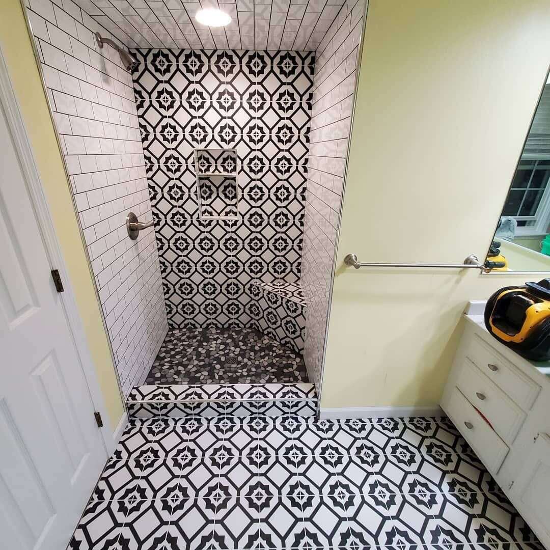 Bathroom with bold black and white patterned tile shower and matching floor