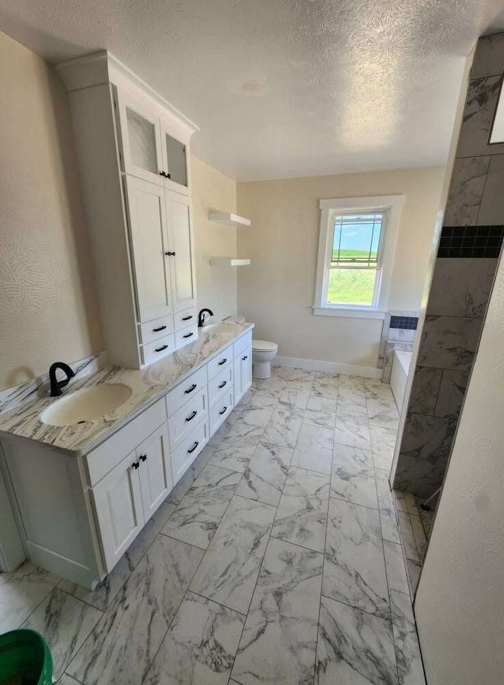 Soaking tub with marble tile surround and dark mosaic accent band