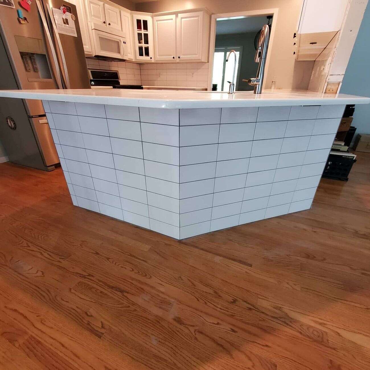 Kitchen island wrapped in stacked white tile