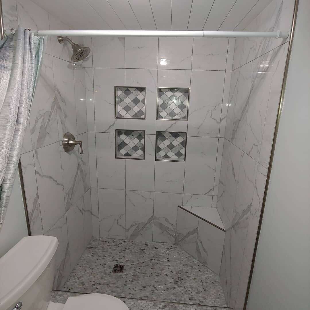 Marble-look shower with four mosaic-lined niches and bench