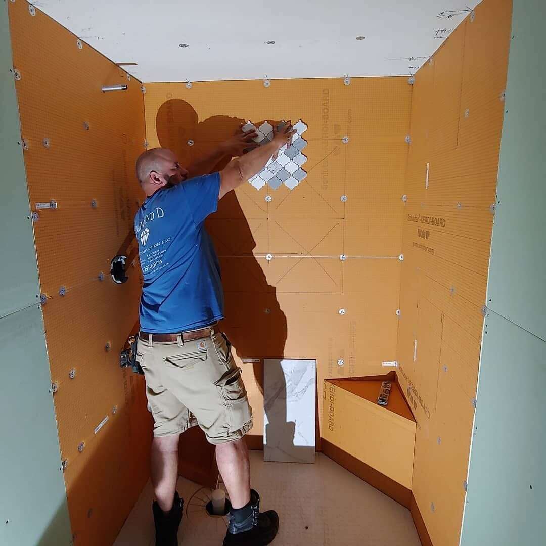 Installer setting tile over waterproofing board