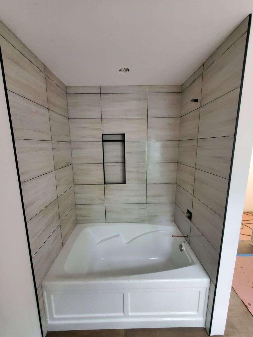 Tub surround in large-format wood-look tile with recessed niche